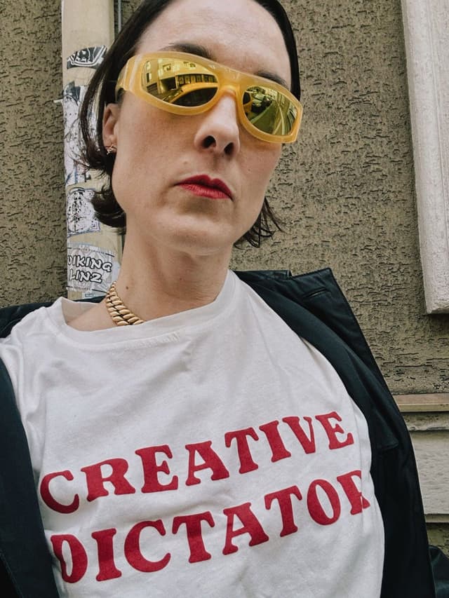 Selfie in yellow mirrored sunglasses and a white "Creative Dictator" T-shirt